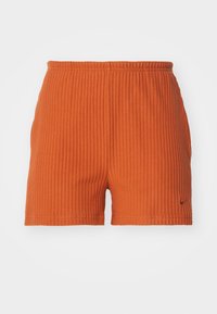 Ribbad orange shorts med elastisk midja. Tygets textur verkar mjuk och hållbar, med en liten logodetalj på sidan.