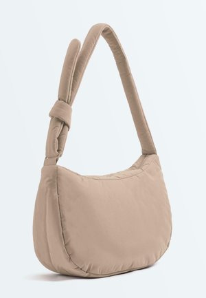 Sac à bandoulière beige rembourré avec une large sangle ajustable et un fond arrondi, présenté sur un fond uni.
