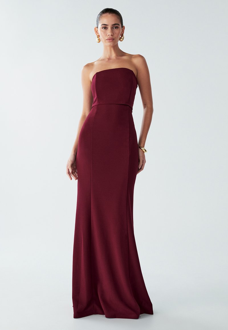 Tehotenské strapless vínovej farby šaty, priliehavý korzet, splývavá sukňa, hladká textúra, detail švov, čisté línie, minimalistický dizajn.