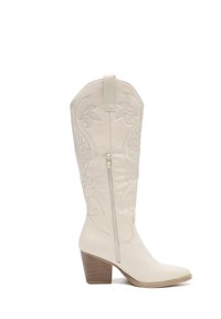 Botas de vaquero color crema con bordado floral, punta afilada, cremallera lateral y tacón bajo. Fabricadas en cuero con una textura suave.