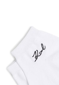 Balti medvilniniai kojinės su struktūrizuota grindų juosta, šone turi juodą siuvinėtą logotipą. Minkšta, kvėpuojanti medžiaga.