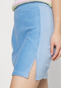 Mini saia de veludo cotelê azul com um tecido texturizado, fendas laterais e um design ajustado. Acabamento suave com uma aparência suave.