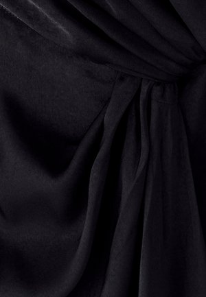 Tela negra con una textura suave, que presenta pliegues drapeados y un detalle anudado en la cintura; la superficie parece blanda y ligeramente lustrosa.