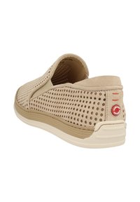 Beige Slipper-Schuh mit perforiertem Textil-Obermaterial, Wildlederakzenten und einer strukturierten Gummisohle mit rotem Logo-Detail an der Ferse.