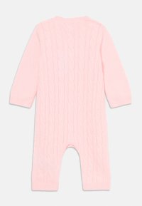 Svetloružový pletený detský overal s dlhými rukávmi a vzorom z kabelkového pletenia, vystavený na bielom pozadí.