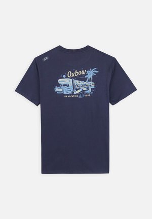 T-shirt en coton bleu marine avec un design graphique d'un van de camping, des palmiers et le texte "Oxbow En Vacances 1985." Manches courtes.