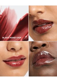 Colore labbra borgogna etichettato "Black Honey Pop" mostrato su tre labbra, evidenziando un finish lucido e tonalità di pelle diverse. Campione testurizzato nell'angolo.