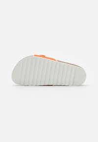 Sandale en daim taupe avec une sangle orange, dotée d'une semelle extérieure texturée blanche avec des rainures et d'un design à bout rond.