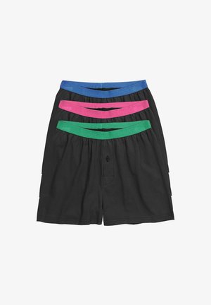 Buste masculin portant un boxer noir avec une ceinture élastique verte et un bouton noir unique au centre devant.