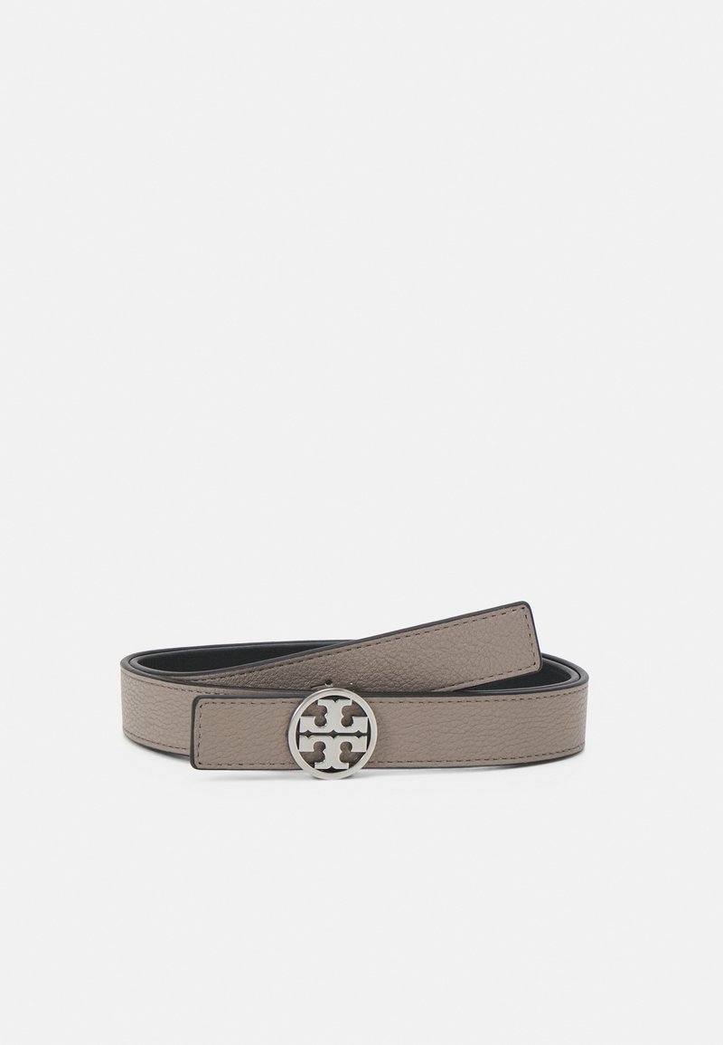 Ceinture en cuir taupe avec une boucle ronde en argent comportant un logo découpé, présentée enroulée sur un fond blanc uni.