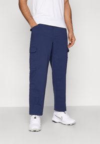 Pantalones cargo azul marino con dos bolsillos laterales y un ajuste holgado. Fabricados con material ligero, presentan una textura suave.