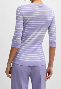 Pulower w paski lawendowy, z rękawami 3/4, wykonany z miękkiej dzianiny. Posiada prążkowany dekolt i mankiety oraz poziome białe paski.