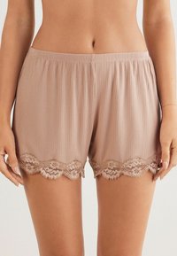 Zachte geribde shorts in een lichte taupe kleur, met een gegolfde kantafwerking aan de zoom. Elastische tailleband voor comfort.