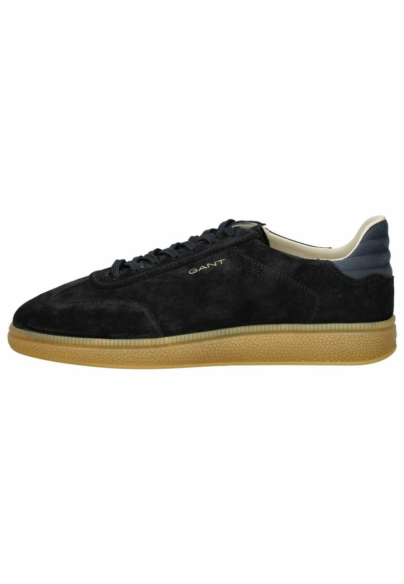 Schwarze Wildledersneaker mit einer strukturierten Gummisohle, einfarbigen Schnürsenkeln und einem grauen Lederakzent an der Ferse. Goldfarbenes Logo-Detail an der Seite.
