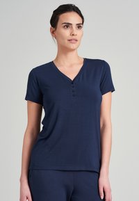Mörkblå T-shirt med kort ärm och V-ringning, samt fyra små knappar längs placket. Mjuk textur, avslappnad passform, enkelt design.