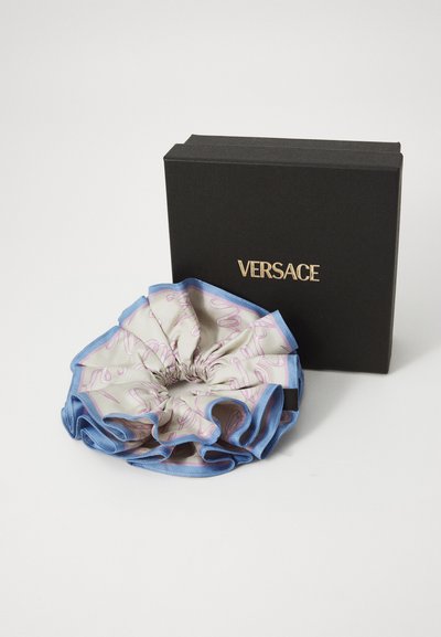Jucătoare de păr din mătase Versace cu margini albastre și un corp gri deschis, prezentând motive abstracte roz, ambalată într-o cutie neagră Versace.