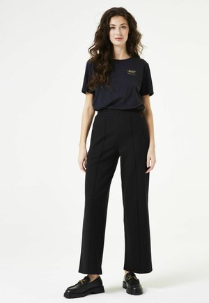 Black wide-leg trousers with a smooth texture, featuring front seam lines and an elastic waistband. Paired with a navy T-shirt and black shoes.
