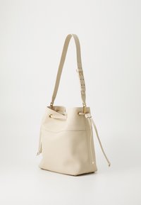Bežová kožená kabelka v tvare vedra s textúrovaným povrchom, nastaviteľným popruhom, zlatými hardware akcentmi a sťahovaním na šnúrku.