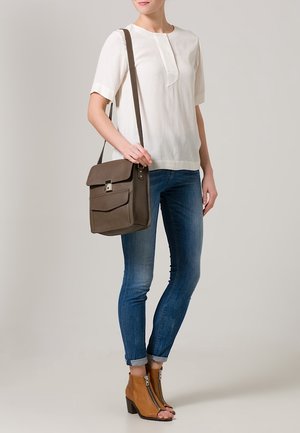 Hvid kortærmet bluse, lysebrun messenger-taske med klap, blå skinny jeans og tan farvede ankelstøvler med lynlås og hæle.