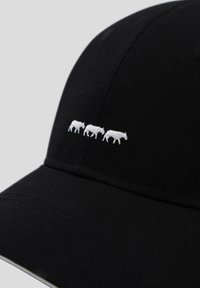 Casquette de baseball noire en coton avec une visière arrondie. Présente trois vaches blanches brodées marchant en ligne sur le panneau frontal.