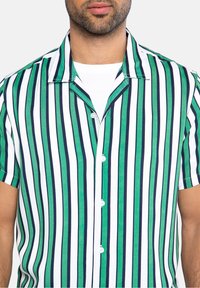 Camicia a maniche corte con righe verticali in verde, blu marino e bianco. Realizzata in tessuto leggero con colletto e chiusura a bottoni.