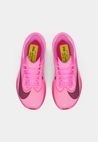 Różowe buty sportowe z siateczkową cholewką, z ciemnoróżowym logo Swoosh, płaskimi sznurówkami i wzorzystym przodem. Jasnożółte oznaczenia w środku.