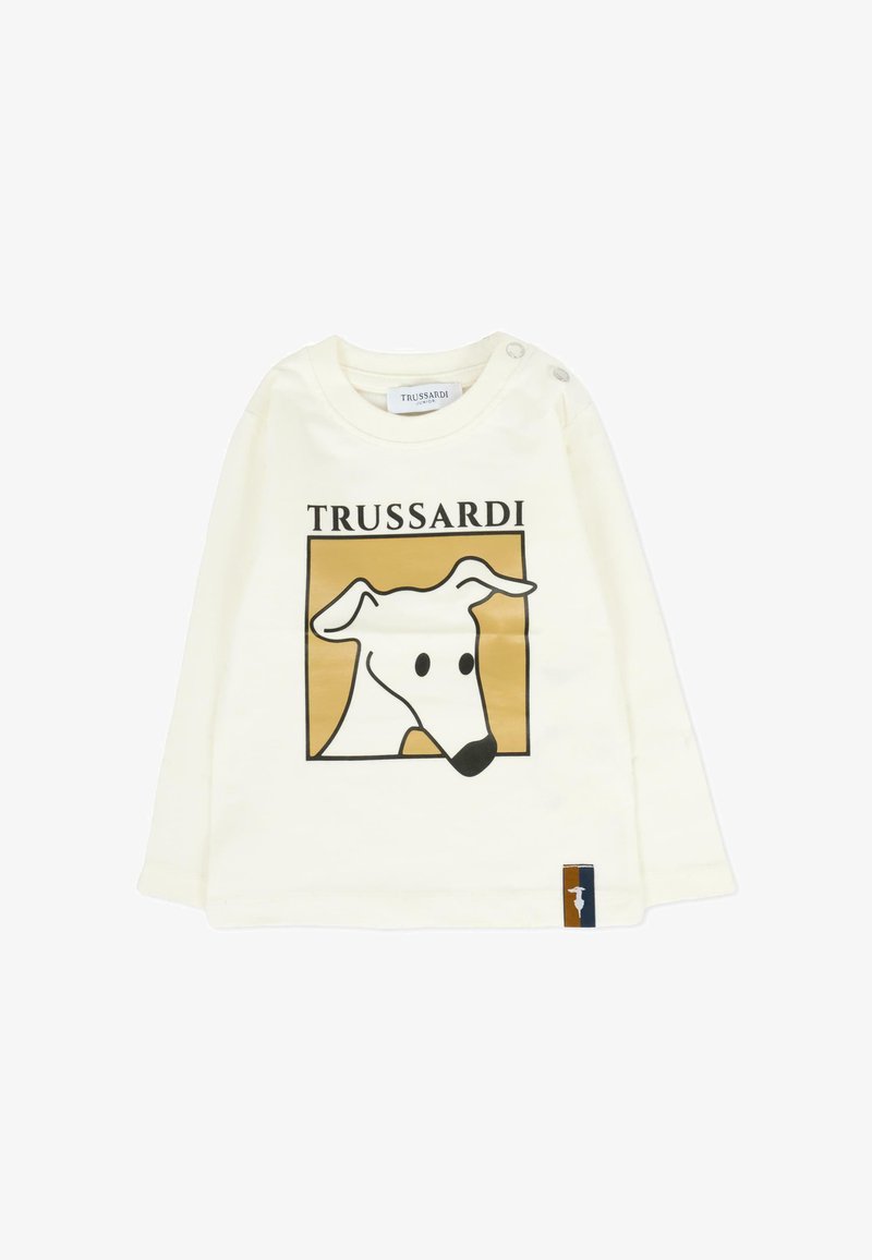 Crème lange mouwen t-shirt met een zwart en gouden hondenafbeelding, uitgerust met een ronde halslijn en knoopdetails op de schouder.