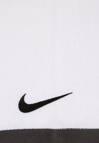 Asciugamano bianco con una finitura texturizzata, caratterizzato da un logo Swoosh Nike ricamato in nero e un accento grigio nella parte inferiore.