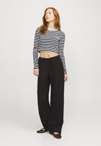 Stripet svart og hvit kortermet langermet topp kombinert med løse svarte bukser med snor i livet og store lommer foran.