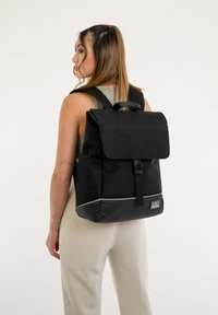 Fekete hátizsák, tartós anyagból készült, fedélz�áras, állítható pántokkal és fényvisszaverő alsó díszítéssel. Oldalsó zsebekkel rendelkezik.