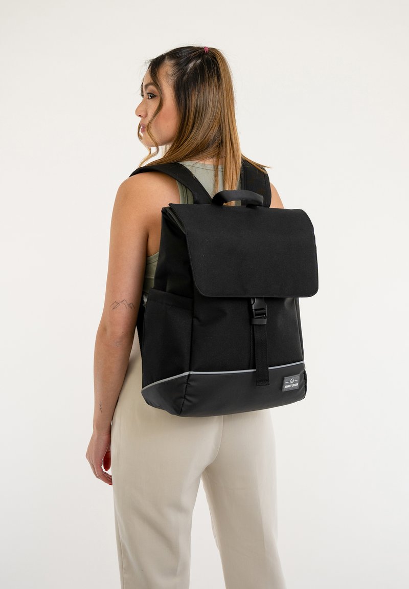 Fekete hátizsák, tartós anyagból készült, fedélzáras, állítható pántokkal és fényvisszaverő alsó díszítéssel. Oldalsó zsebekkel rendelkezik.