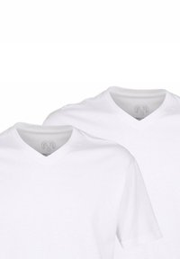 Weiße Baumwoll-T-Shirts mit kurzen Ärmeln, V-Ausschnitt-Design, glatte Textur und zwei sichtbaren Ausschnitten für den Hals. Keine Grafiken oder Markierungen vorhanden.