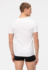 Witte T-shirt met korte mouwen in een getailleerd ontwerp, gemaakt van katoen, met een soepele textuur en een ronde hals, gecombineerd met zwarte shorts.