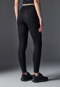 Black leggings with a fitted design, made of a smooth, stretchy material. Features a high waistband and flatlock seams for comfort.