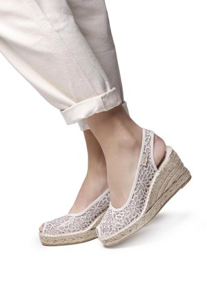 White lace open-toe wedges with a jute platform, featuring floral patterns and a slingback design. Lightweight with a natural texture.
