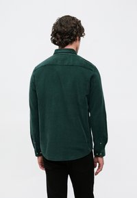 Roheline fliiskangast särk, millel on nööpidega kaelus, pikad varrukad nööbitavate mansettidega ja tekstureeritud kangas. Esitatud on selja vaade.