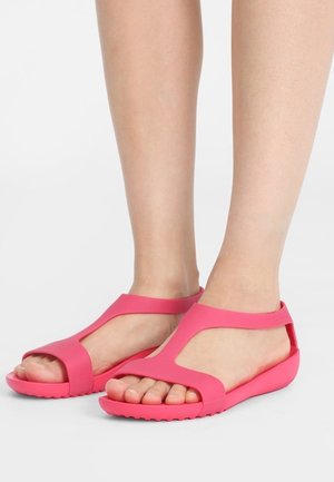 Lyserøde sandaler af fleksibel gummi med T-rem, åbne tæer og teksturerede såler med lav hæl.