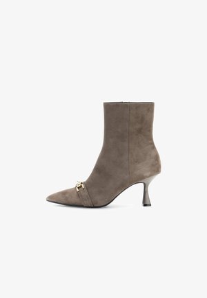 Bruine suède enkelboot met een spitse neus, een glanzende hak en dubbele smalle bandjes met een goudkleurig accent aan de voorkant.