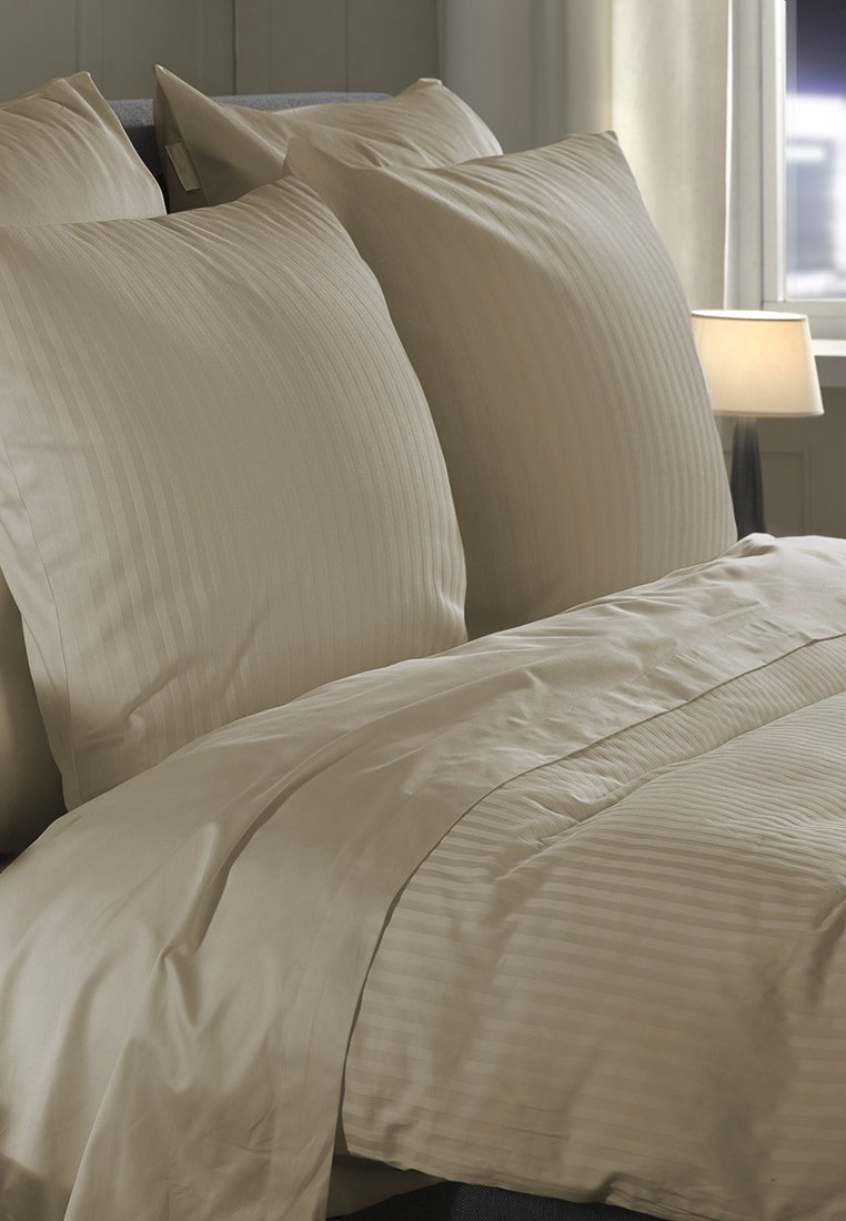 Beige Bettwäsche-Set mit gestreifter Textur, bestehend aus zwei passenden Kissenbezügen und einem Bettdeckenbezug, auf einem Bett mit sanfter Beleuchtung angeordnet.