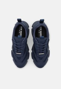 Par de zapatillas azul marino de Steve Madden con paneles de malla, suelas gruesas, cordones e insoles de marca, mostradas desde una vista superior sobre un fondo blanco.
