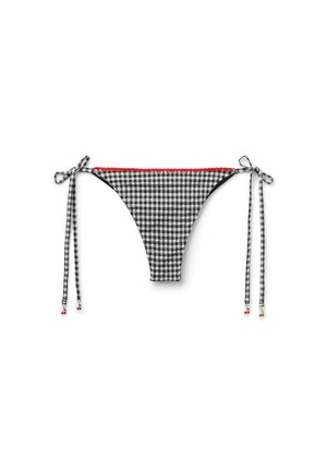Schwarze und weiße quadratische Bikini-Unterhose mit rotem Besatz, seitlichen Bindebändern zur Anpassung und dekorativen Charms an den Enden.