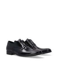 Zwarte leren dresschoenen met een gladde afwerking, ronde neus, vier oogjes en dunne veters. Lage hak en subtiele stikdetails.