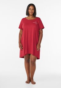 Red, short-sleeve nightgown with a rounded neckline and slightly curved hem. Features text "BE BRAVE" in a decorative font on the chest. Soft fabric.
