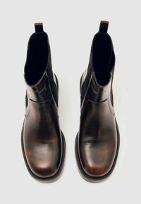 Rudos odinės kulkšnės botai su elastingais šonais, traukimo kilpute ir lygiu paviršiumi. Apvalus toe ir juodas guminis padas, užtikrinantis sukibimą.