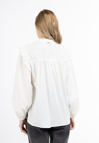 Witte blouse met geschulpte schouderdetails en een gathered rug, voorzien van lange pofmouwen en een ronde halslijn. Glad, lichtgewicht stof.