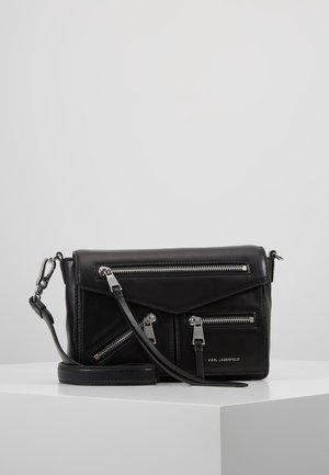 Czarna skórzana torba na ramię z wieloma srebrnymi zamkami i regulowanym paskiem, z logo "Karl Lagerfeld" na przedniej kieszeni.