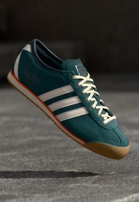 Tarkaszínű bársonybőr sneaker fehér bőr csíkokkal, világosszürke fűzőkkel, narancssárga részletekkel és texturált gumitalppal. Hétköznapi dizájn.