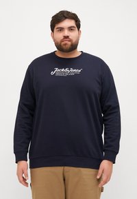 Marineblauwe sweatshirt met lange mouwen, ronde hals en logo aan de voorkant. Gemaakt van een zachte stof met ribgebreide cuffs en zoom. Casual pasvorm.