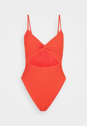 Raudonas dirželiu viengubas maudymosi kostiumas su sukurtu priekiniu dizainu, reguliuojamais dirželiais ir iškirpimu juosmens srityje. Vientisas tekstūros paviršius ir aukštai kirpti keliai.