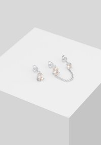 Pendientes de plata con piedras en forma de pera de color naranja claro, que presentan dos aretes conectados por una fina cadena. Superficie lisa y acabado pulido.